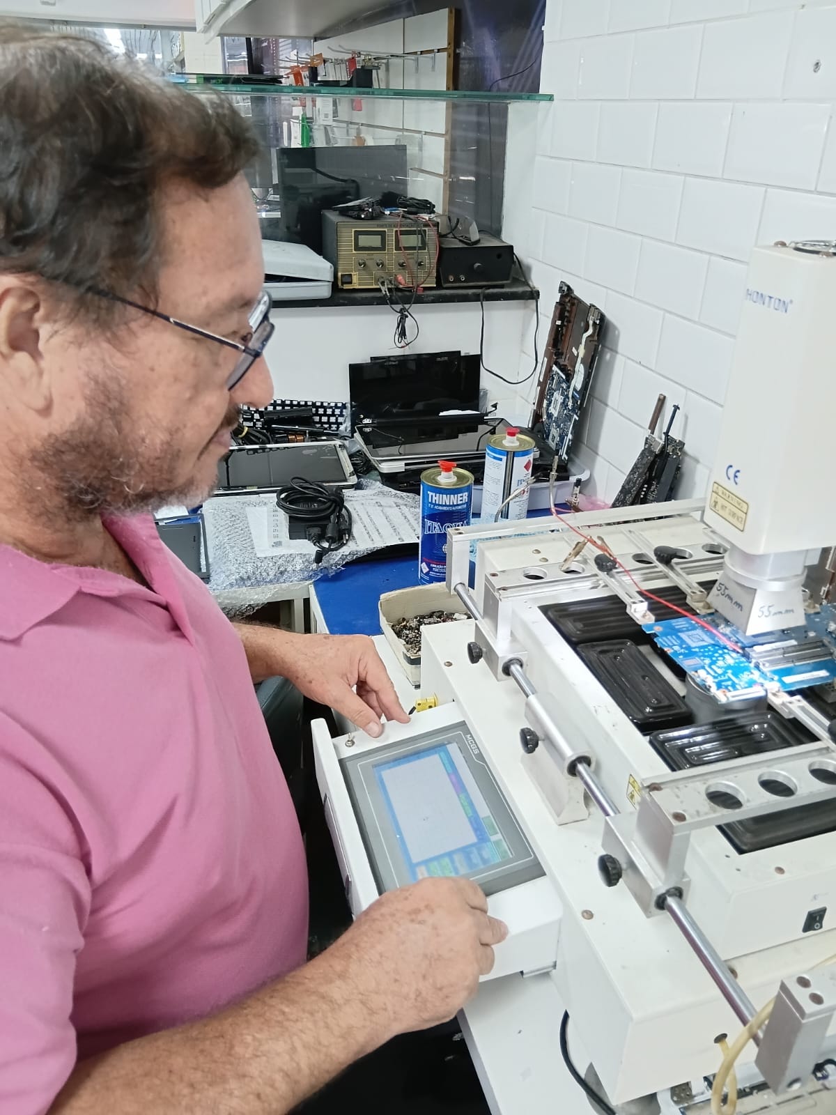 Técnico operando estação de reballing com painel digital